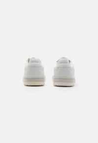 Baskets blanches avec une tige en cuir lisse, bout arrondi et semelle en caoutchouc beige. Logo "HUGO" embossé au niveau du talon.