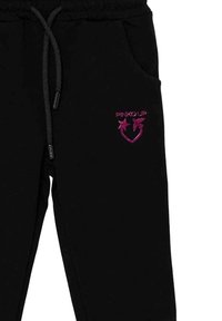 Pantaloni da allenamento neri con tasche frontali, vita con cordoncino e logo "PINKO UP" rosa con una stella e un uccello sopra un cuore sulla coscia sinistra.