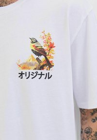 Bijela majica s ilustracijom šarene ptice, jesenskog lišća i planine, uz crni tekst ispod na japanskim znakovima.