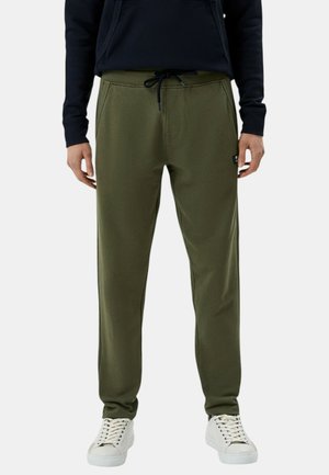 Pantaloni jogger verde oliva con cintura regolabile, tasche laterali e una texture liscia, abbinati a sneakers bianche.