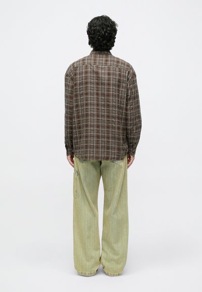 Brązowa koszula w kratę z długimi rękawami i karczkiem z tyłu oraz jasnooliwkowe spodnie o szerokich nogawkach, z bocznym zamkiem i fakturowaną tkaniną.
