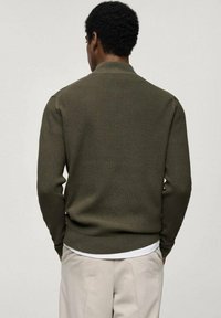 Pulover ribbed de culoare verde măsliniu, cu guler înalt, mâneci lungi și talie ajustată. Design minimalist cu țesătură texturată.