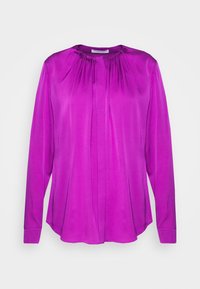 Klart lila långärmad blus med samlad halsringning och dold framknäppning på en enfärgad ljus bakgrund.