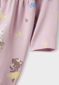 Camisa de algodón rosa claro con divertidas ilustraciones de un oso en tutú, un conejo, estrellas, corazones y lazos en varios colores.