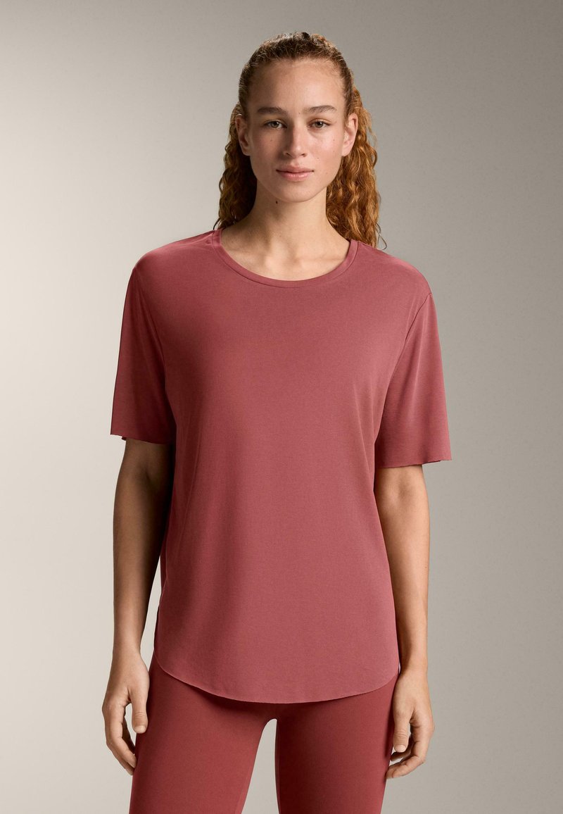 T-shirt à manches courtes et col rond de couleur rose muté, fabriqué en tissu doux. Présente une coupe décontractée et un ourlet légèrement arrondi.