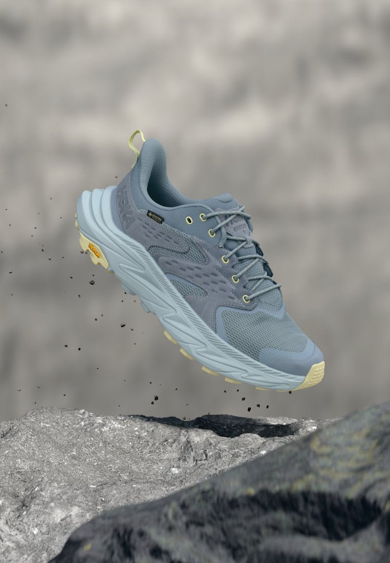 Chaussure de course bleu clair avec tige texturée, accents verts et semelle amortie. Dispose d'une semelle extérieure à haute adhérence et de détails réfléchissants.