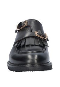 Zwarte leren schoen met franjes, twee metalen gespen, ronde neus en een gestructureerde zool. Het ontwerp benadrukt minimalisme en functionaliteit.