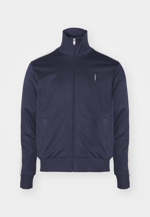 Námornícky zipsový kabát s vysokým golierom, dvoma postrannými vreckami a kontrastnými pruhmi pozdĺž rukávov. Vyrobený z jemnej, hladkej látky.