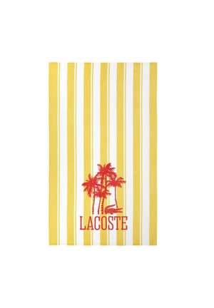 Serviette à rayures verticales jaunes et blanches avec des palmiers rouges, un logo de crocodile et le texte "LACOSTE" centré près du bas.