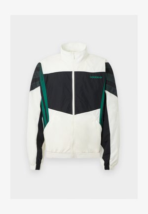 Balta un melna vēja jaka ar zaļiem akcentiem, ar rāvējslēdzēja aizdari, augstu apkakli, elastīgām aprocēm un horizontālām svītrām uz piedurknēm.