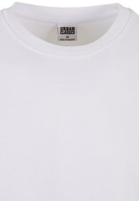 Biela bavlnená tričko s okrúhlym výstrihom. Nálepka hovorí "URBAN CLASSICS," veľkosť M. Hladká textúra, bez viditeľných vzorov alebo akcentov.