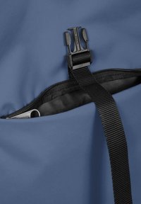 Borsa in tessuto blu con tasca con zip, dotata di una tracolla nera regolabile e di un gancio di plastica. All'interno si intravede un oggetto metallico.