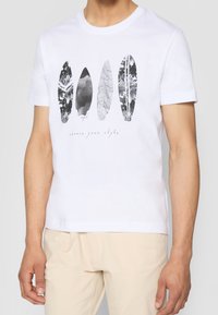 Witte katoenen T-shirt met vier decoratieve surfplankafdrukken in zwart, grijs en wit met abstracte patronen en de tekst "kies je stijl."