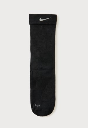 Sort Nike crew-ssok med gråt swoosh-logo nær manchet og størrelsesangivelse "M/L" på tåen, vist mod en hvid baggrund.