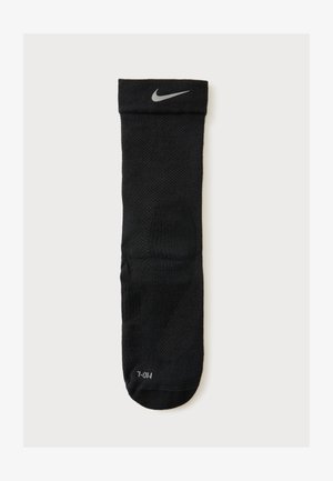 Μαύρη κάλτσα Nike crew με γκρι λογότυπο Swoosh κοντά στο μανσέτα και ένδειξη μεγέθους "M/L" στο δάχτυλο, εμφανίζεται σε λευκό φόντο.