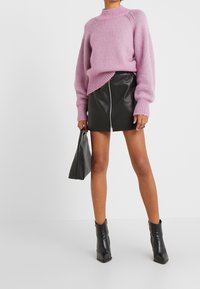 Světle růžový pletený svetr s kulatým výstřihem, doplněný černou koženou mini sukni se zipem na přední straně. Stylizováno s černými kotníkovými botami.