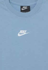 Svetlomodré tričko Nike s okrúhlym výstrihom, na prednej strane s bielym logom Nike. Vyrobené z hladkej, jemnej tkaniny.