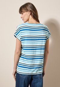 Camiseta de rayas con mangas cortas, que presenta rayas alternas en azul claro, azul oscuro y negro. Tela suave; se muestra la vista trasera.
