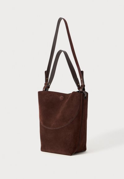 Brown suede tote bag with a smooth leather strap. The bag features a rounded flap design and a minimalist aesthetic.