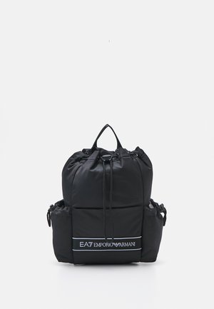 Sac à dos noir à cordon avec poches latérales et logo blanc EA7 Emporio Armani sur la poche avant, sur fond blanc.