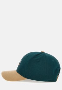 Cappello di stoffa verde scuro con visiera beige, dotato di fori per la ventilazione e di un piccolo bottone in cima. Testo ricamato sul davanti.