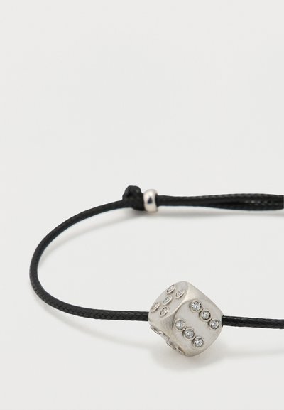 Juodas pintas virvelės apyrankė su sidabrinės spalvos kauliuko žavesiu, kurio šonuose yra skaidrūs kristalai kaip puošmena.