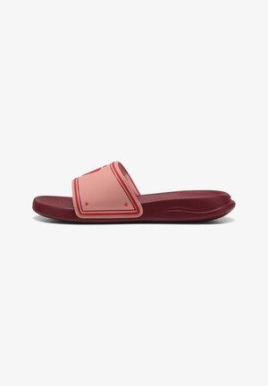 Sandale à glissière rose clair avec une large sangle, ornée d'accents en forme de cœur et d'une semelle bordeaux. Fabriquée en caoutchouc texturé pour le confort et la durabilité.