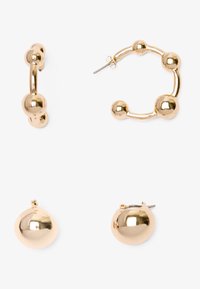 Pendientes de metal dorado con dos diseños: un aro con acentos esféricos y sencillos botones esféricos, ambos con un acabado pulido.
