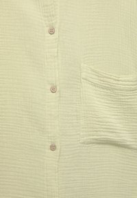 Lichtgroene, gestructureerde button-up shirt met een pocket, voorzien van vijf knopen en een subtiele geribbelde patroon door de stof.