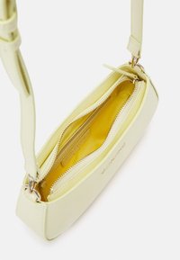 Yellow leather handbag with a textured surface, featuring a zippered closure, interior pocket, and shoulder strap. Gold-tone hardware accents.