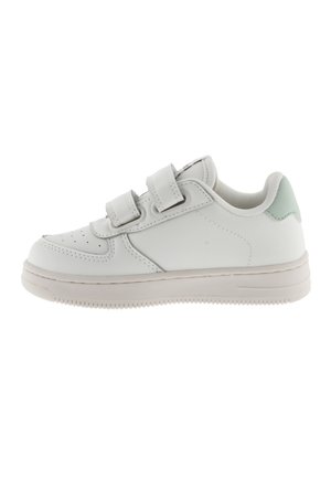 Zapatilla blanca con un upper de cuero suave, dos correas de Velcro, una puntera perforada y un acento verde claro en el talón.