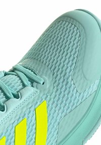 Chaussure de sport bleu clair en tissu texturé, avec des lacets et trois rayures verticales jaune vif sur le côté.