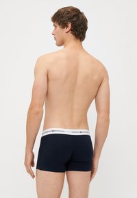 Férfi sötét navy színű boxer alsónadrág, pamutból készült, fehér derékpánttal, amelyen a Tommy Hilfiger logó található. Simaság jellemzi, testhezálló fazon.