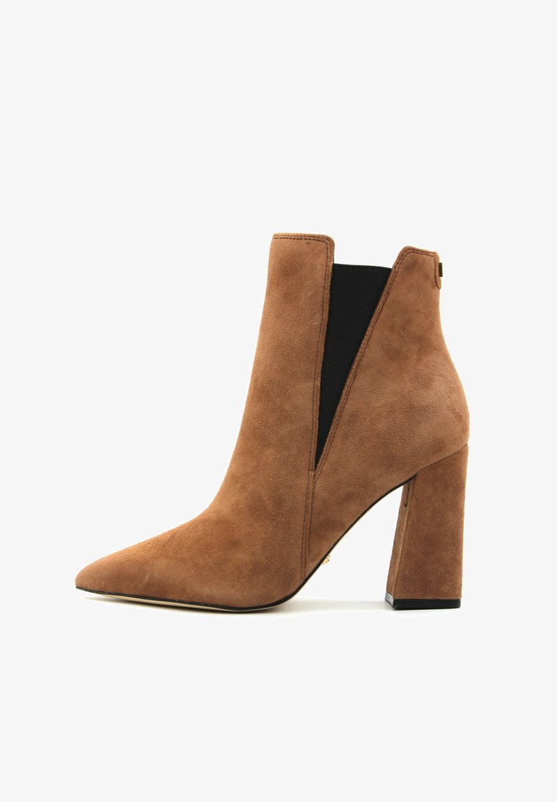 Hnědá suedená kotníková bota s špičatou špičkou, elastickými bočními panely a blokovým podpatkem. Má V-řez design pro elegantní vzhled.