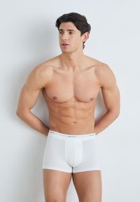 Weiße GANT Boxer Shorts bieten eine enge Passform, ein weiches Baumwollmaterial und einen Bund mit Logodetails. Glatte Oberfläche, minimalistisches Design.