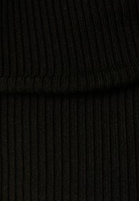 Tissu noir à côtes avec une finition texturée, présentant des rayures verticales. Le matériau semble doux et flexible.