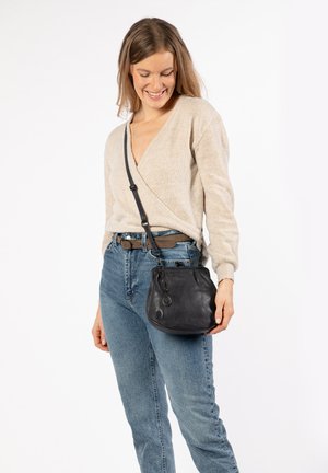 Borsa a secchiello nera in pelle con forma curvata, tracolla regolabile e piccolo dettaglio pendente. La borsa ha una superficie liscia e un design minimalista.