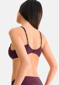 Paarse beha met verstelbare bandjes, gegolfde kanten en een rechte rugontwerp, voorzien van gouden hardware en een gladde stofafwerking.