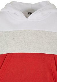 Felpa con cappuccio bianco, parte centrale grigia e fondo rosso. Realizzata in tessuto morbido con una texture liscia e tasca frontale.