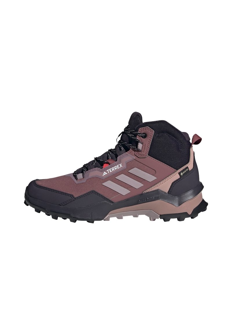 Burgundi és fekete felsőrésszel rendelkező túracipő, szintetikus anyagokból, magas bokatámasszal, barázdált talppal és kiemelkedő fehér Adidas csíkkal.