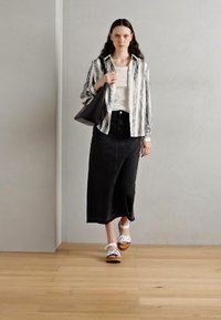 Svart denim midi-skjørt, hvit stripete skjorte med knapper, hvite sandaler og en svart tote-veske. Glatte teksturer, uformell design og nøytrale farger.