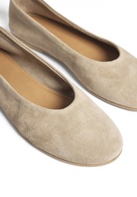Beige Wildleder Ballerinas mit einer runden Spitze und ausgeschnittenen Seiten, ausgestattet mit einem glatten Innenfutter und einer flexiblen Sohle.