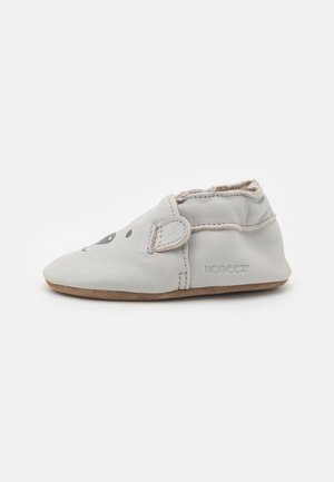 Grå lærslipper med en myk såle, med et lekent dyreansiktsdesign og borrelåsstropp for enkel bruk. Merkevarelogo på siden.