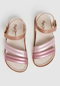 Lichte sandalen met een bruine leren band en drie glanzende roze synthetische banden over de bovenkant. Beigekleurige binnenzool, platte bruine zool.