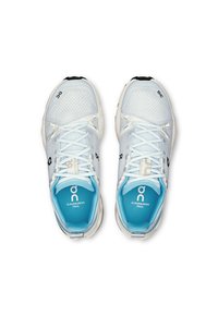 Weiße Netz-Laufschuhe mit hellblauen Akzenten, strukturierten Oberflächen, glatten Schnürsenkeln und einer schwarzen Außensohle, die das Logo und die Modellbezeichnung trägt.