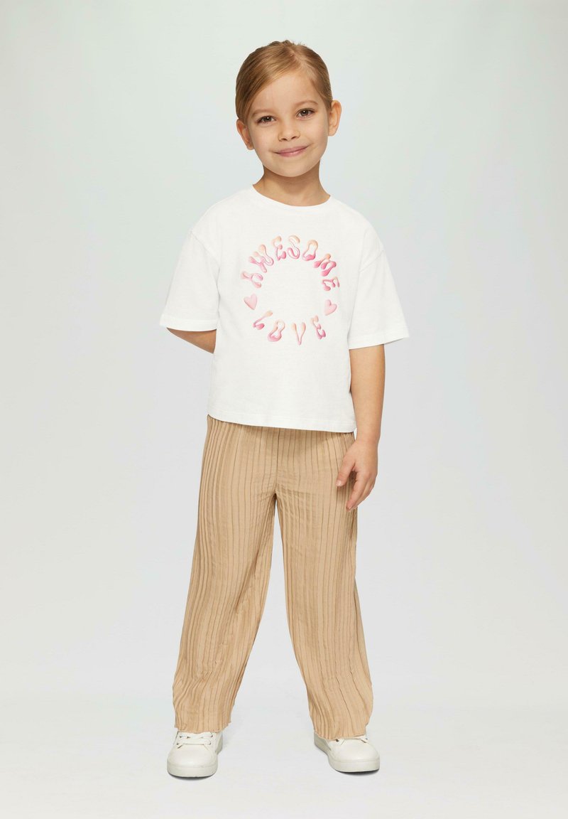 Weißes Kurzarm-T-Shirt mit "Awesome Love" in Pink, kombiniert mit beigen, gerippten, weiten Hosen. Das Outfit wird durch weiße Sneakers abgerundet.