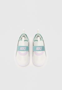 Baskets blanches Nike à enfiler avec une sangle vert menthe, des accents violets, un tissu texturé, une semelle plate et des languettes pour un enfilage facile.