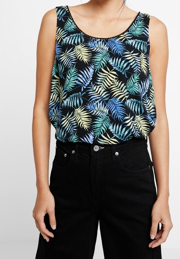 Haut noir sans manches avec imprimé de feuilles tropicales bleues, vertes et jaunes porté avec un pantalon noir taille haute sur une personne debout.