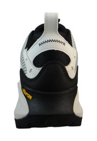 Zapatilla deportiva en blanco y negro con parte superior de malla estructurada, suela de goma y un logo de Vibram en el talón. Los acentos cosidos realzan el diseño.