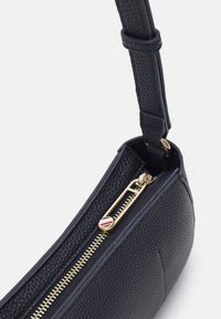 Borsa in pelle effetto tessuto blu navy con cerniera dorata e tirante, dotata di tracolla staccabile e interno liscio.